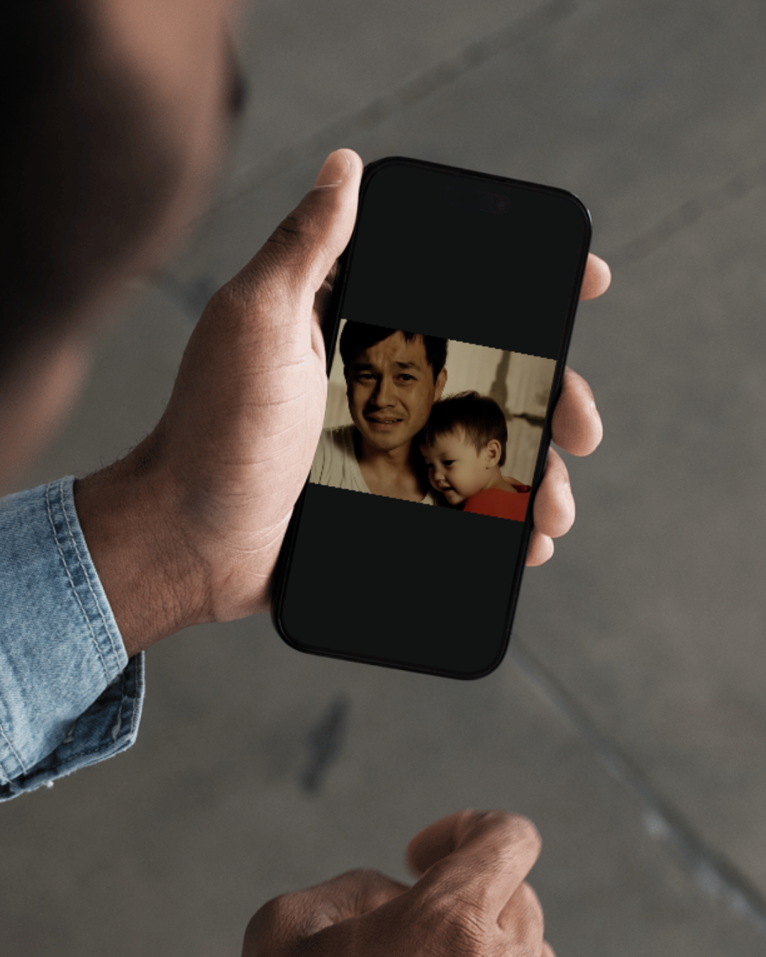 asiatischer mann, müde. schaut trauig in die kamer. keines kind sitzt auf seinem schoß